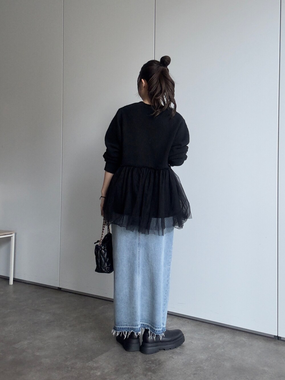 ブラック系のショルダーバッグ、ブルー系のデニムスカート、ブラック系のブーツを着用したレディースの秋コーディネートの3枚目の写真