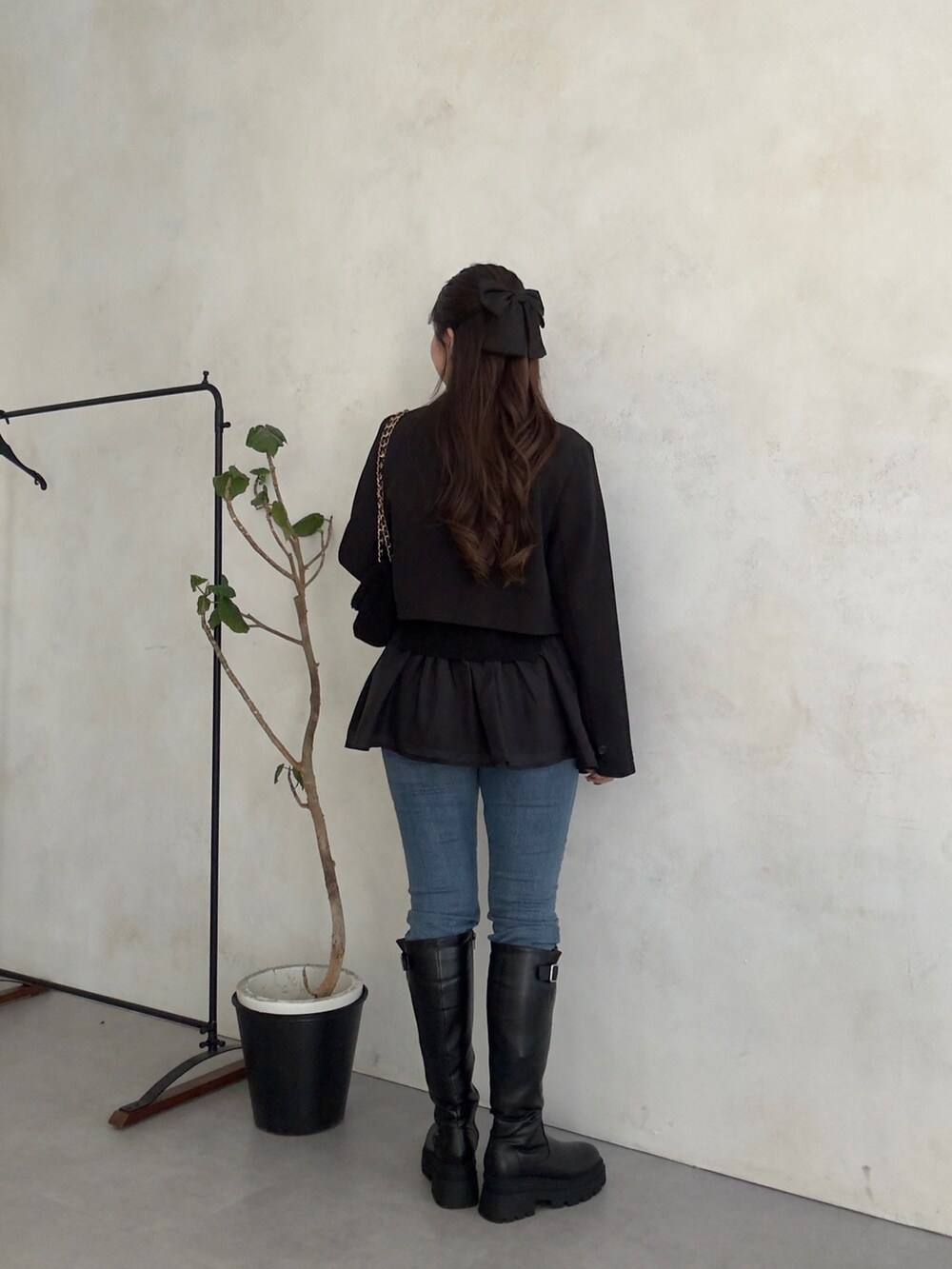 ブラック系のテーラードジャケット、ブルー系のデニムパンツ、ブラック系のブーツを着用したレディースの秋コーディネートの3枚目の写真