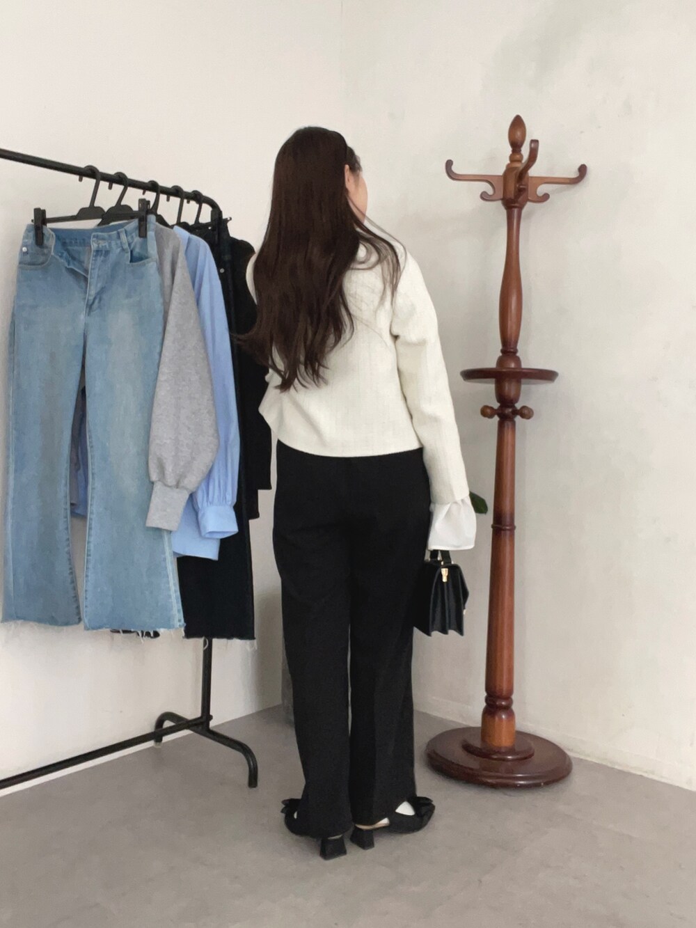 ホワイト系のノーカラージャケット、ホワイト系のニット/セーター、ブラック系のスラックスを着用したレディースの冬コーディネートの3枚目の写真