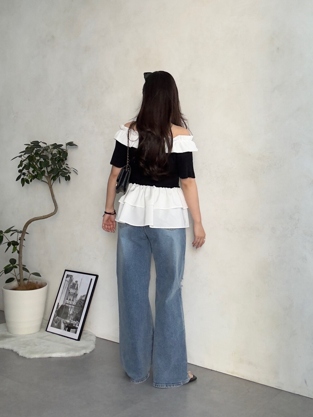 ブラック系のトートバッグ、ブルー系のデニムパンツ、ブラック系のサンダルを着用したレディースの夏コーディネートの3枚目の写真