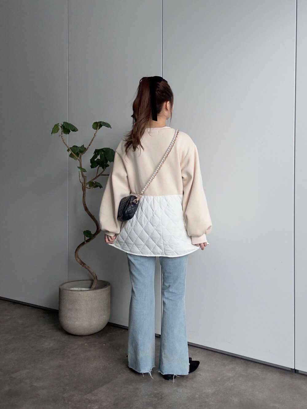 ベージュ系のTシャツ/カットソー、ブラック系のショルダーバッグ、ブルー系のデニムパンツを着用したレディースの冬コーディネートの3枚目の写真