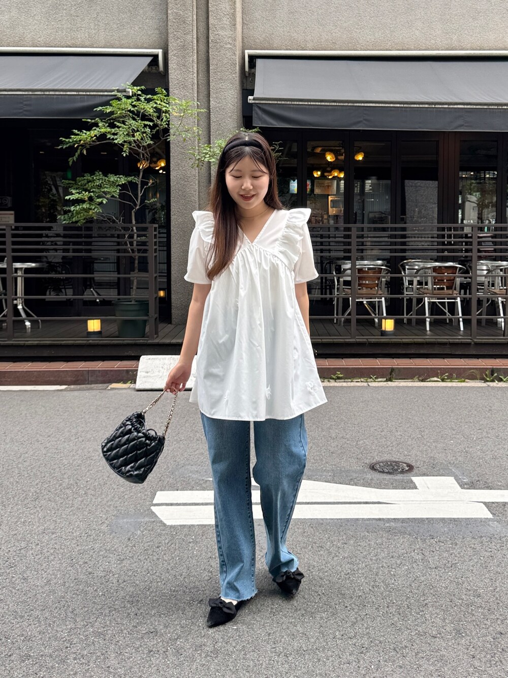 ブルー系のデニムパンツ、ブラック系のパンプス、ホワイト系のシャツ/ブラウスを着用したレディースの夏コーディネートの2枚目の写真