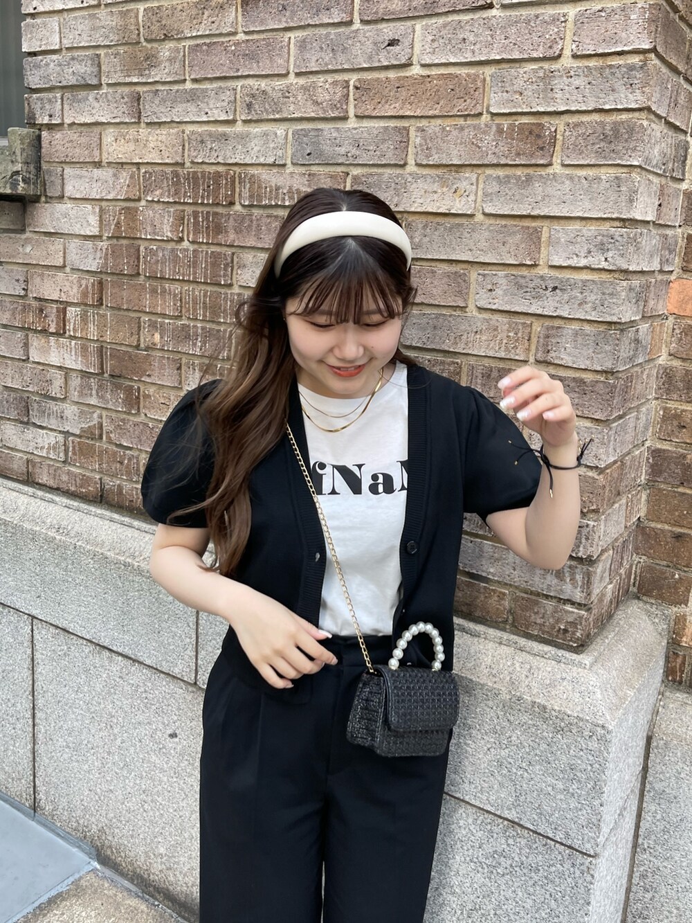 ブラック系のショルダーバッグ、ホワイト系のTシャツ/カットソー、ブラック系のカーディガン/ボレロを着用したレディースの春コーディネートの2枚目の写真