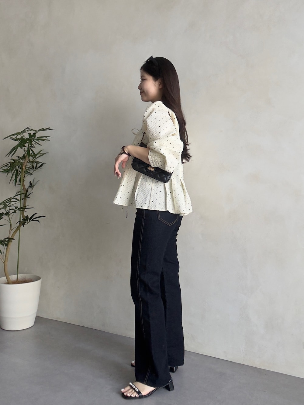 ブラック系のトートバッグ、ブルー系のデニムパンツ、ブラック系のサンダルを着用したレディースの春コーディネートの2枚目の写真