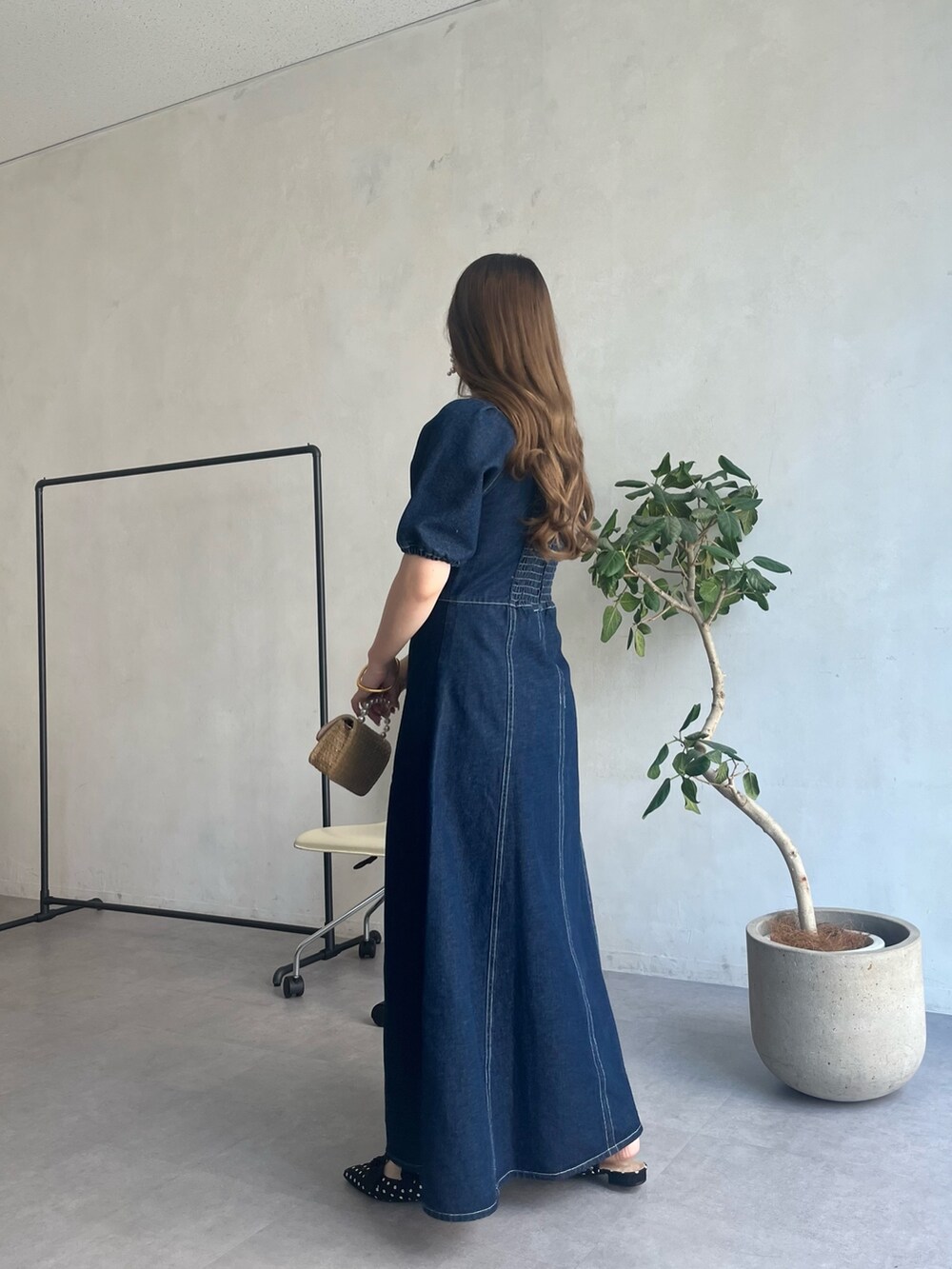 ブルー系のワンピース、ブラック系のパンプス、ゴールド系のネックレスを着用したレディースの春コーディネートの2枚目の写真