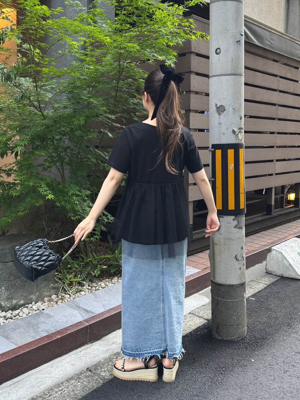 ブラック系のショルダーバッグ、ブラック系のTシャツ/カットソー、ブルー系のデニムスカートを着用したレディースの春コーディネートの3枚目の写真