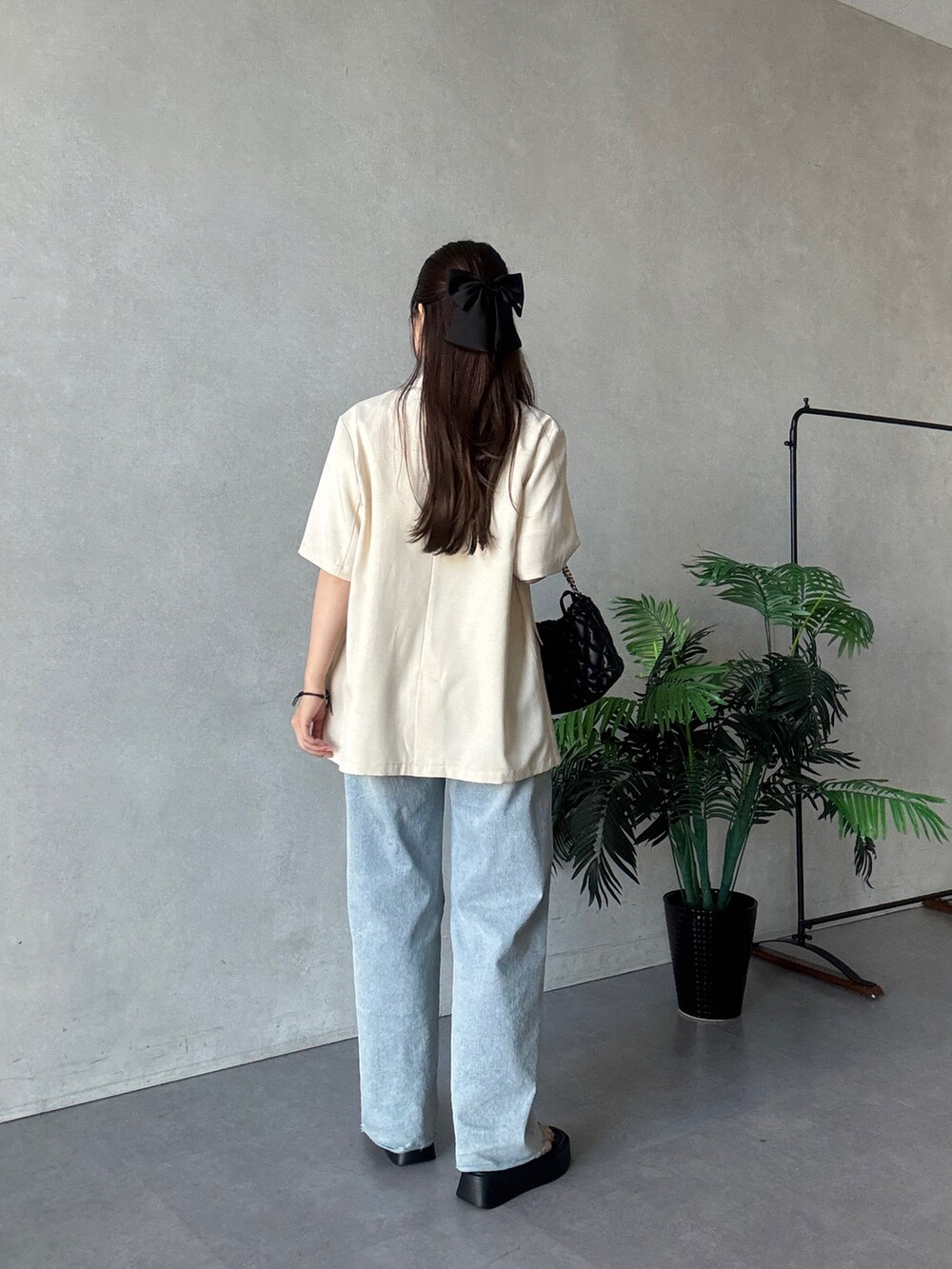 ブラック系のテーラードジャケット、ホワイト系のTシャツ/カットソー、ブルー系のデニムパンツを着用したレディースの夏コーディネートの3枚目の写真