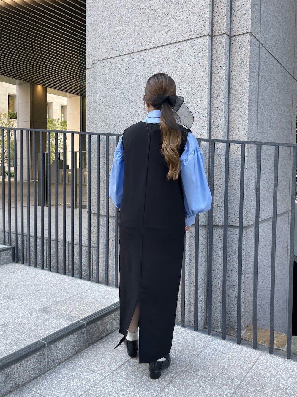 ブルー系のシャツ/ブラウス、ブラック系のローファー、ブラック系のジャンパースカートを着用したレディースの春コーディネートの2枚目の写真