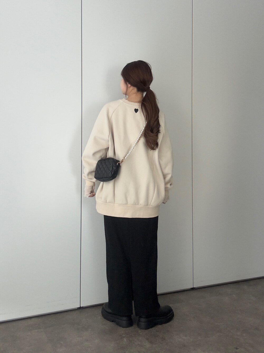 ホワイト系のスウェット、ブラック系のショルダーバッグ、ブラック系のスカートを着用したレディースの冬コーディネートの3枚目の写真