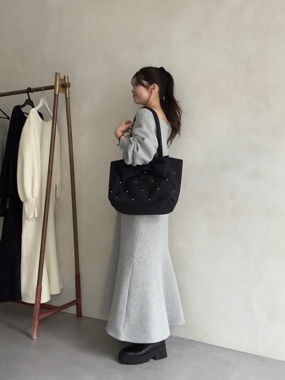 ブラック系のトートバッグ、ブラック系のブーツ、グレー系のワンピースを着用したレディースの秋コーディネートの2枚目の写真