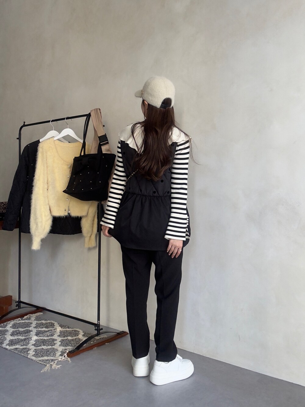 ホワイト系のニット/セーター、ブラック系のベスト、ブラック系のその他パンツを着用したレディースの秋コーディネートの3枚目の写真