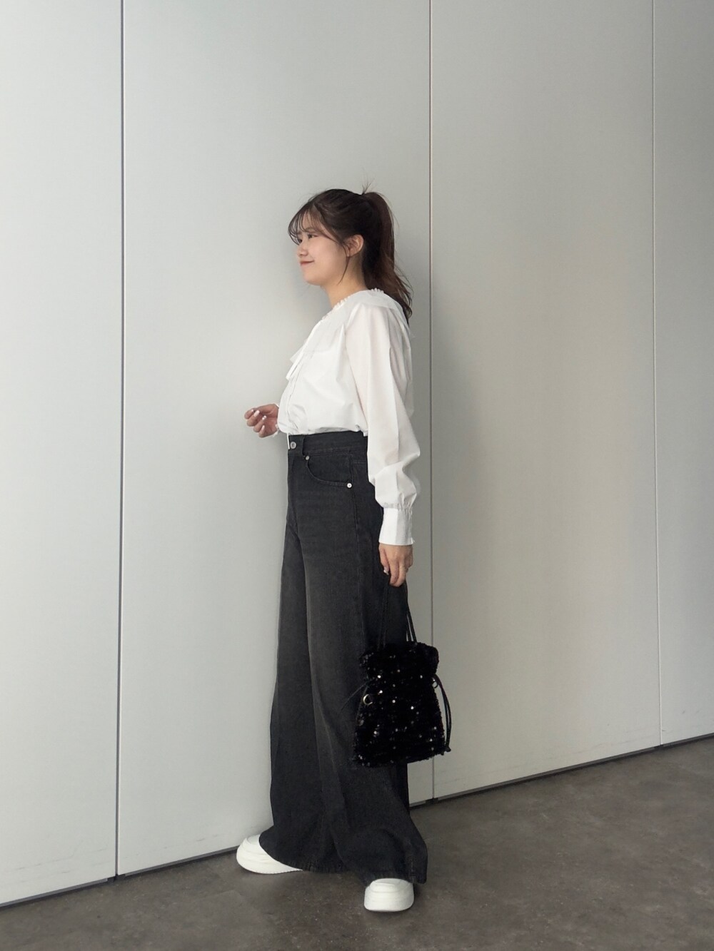 ブラック系のデニムパンツ、ホワイト系のスニーカー、ブラック系のショルダーバッグを着用したレディースの冬コーディネートの2枚目の写真