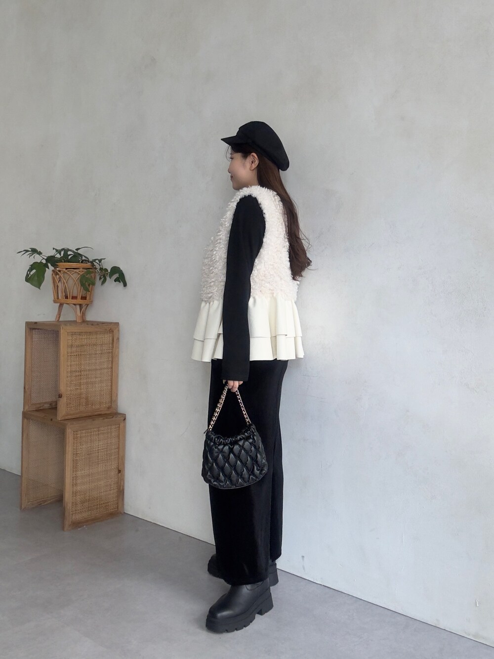 ホワイト系のベスト、ブラック系のスカート、ブラック系のブーツを着用したレディースの秋コーディネートの2枚目の写真