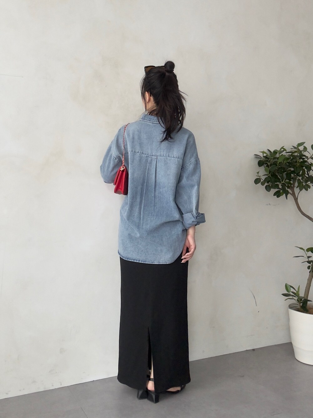 レッド系のトートバッグ、ブラック系のスカート、ブラック系のサンダルを着用したレディースの春コーディネートの3枚目の写真