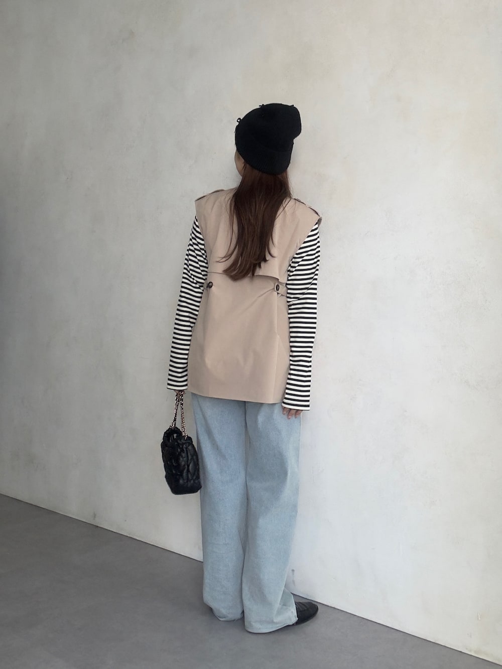 ホワイト系のキャミソール、ブルー系のデニムパンツ、ベージュ系のベストを着用したレディースの夏コーディネートの3枚目の写真