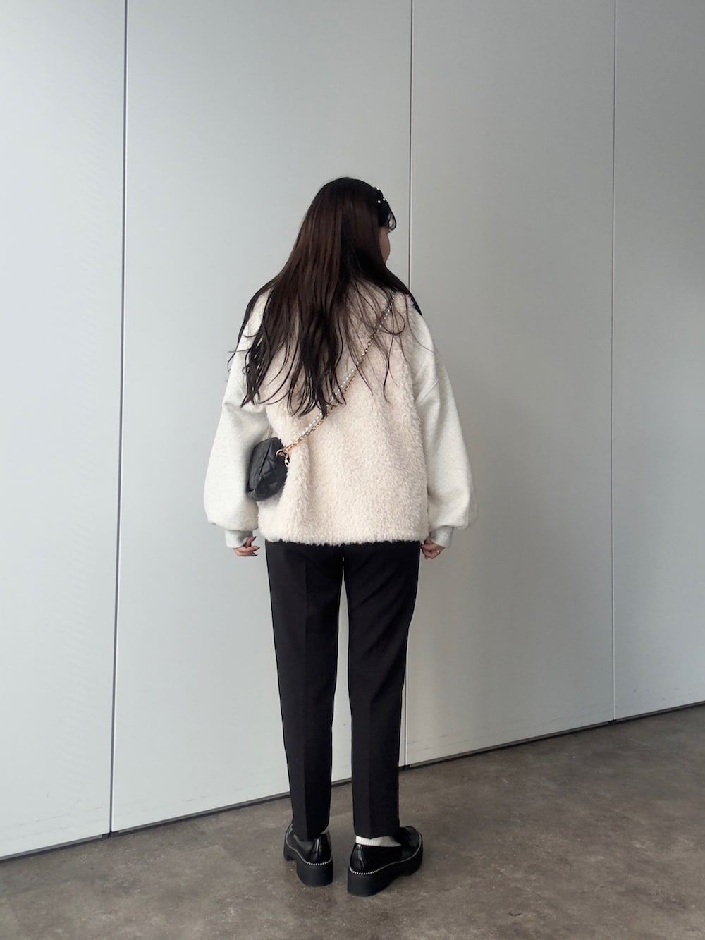 グレー系のスウェット、ホワイト系のベスト、ブラック系のその他パンツを着用したレディースの秋コーディネートの3枚目の写真