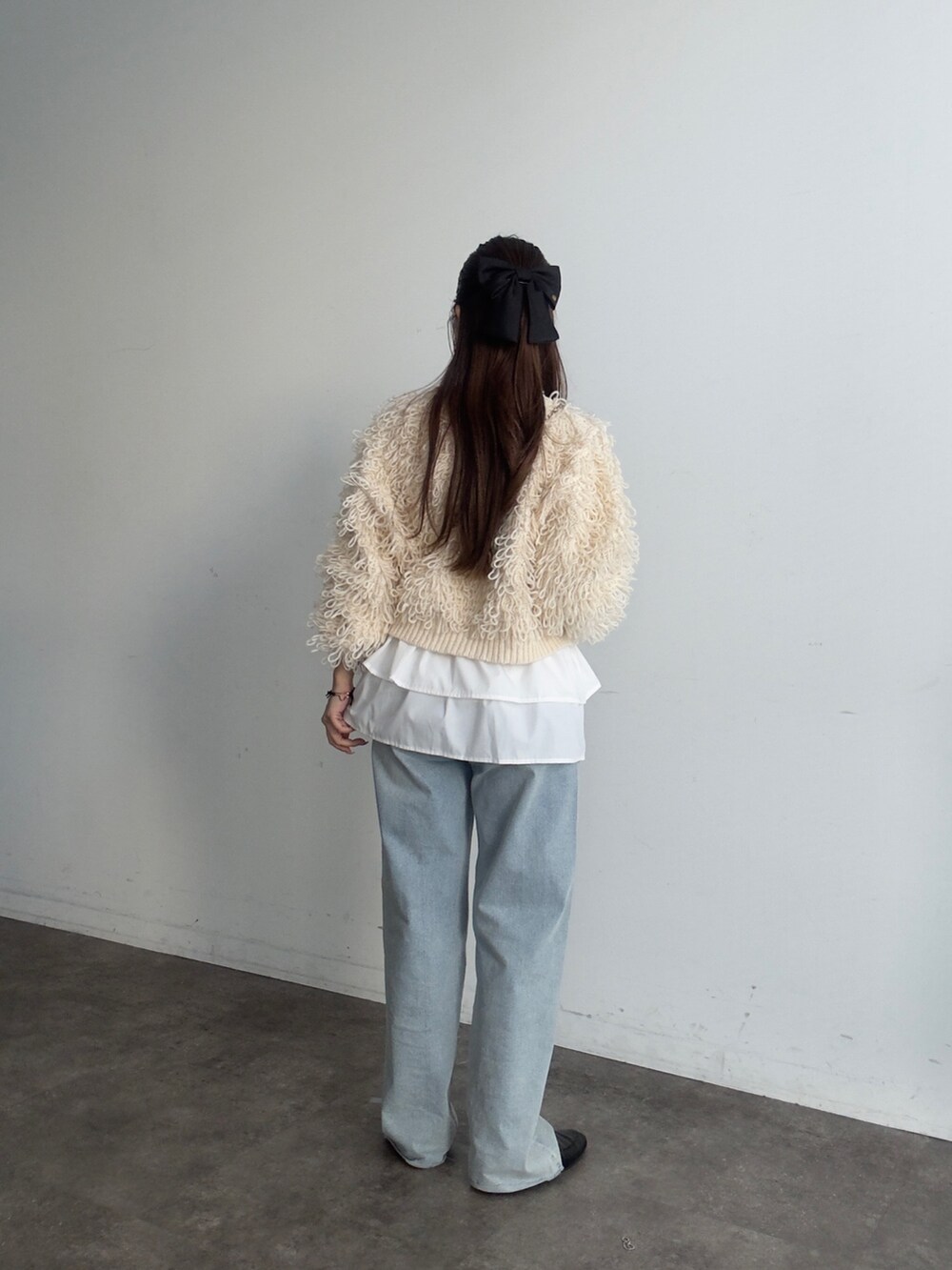 ホワイト系のスカート、ホワイト系のカーディガン/ボレロ、ブルー系のデニムパンツを着用したレディースの秋コーディネートの3枚目の写真