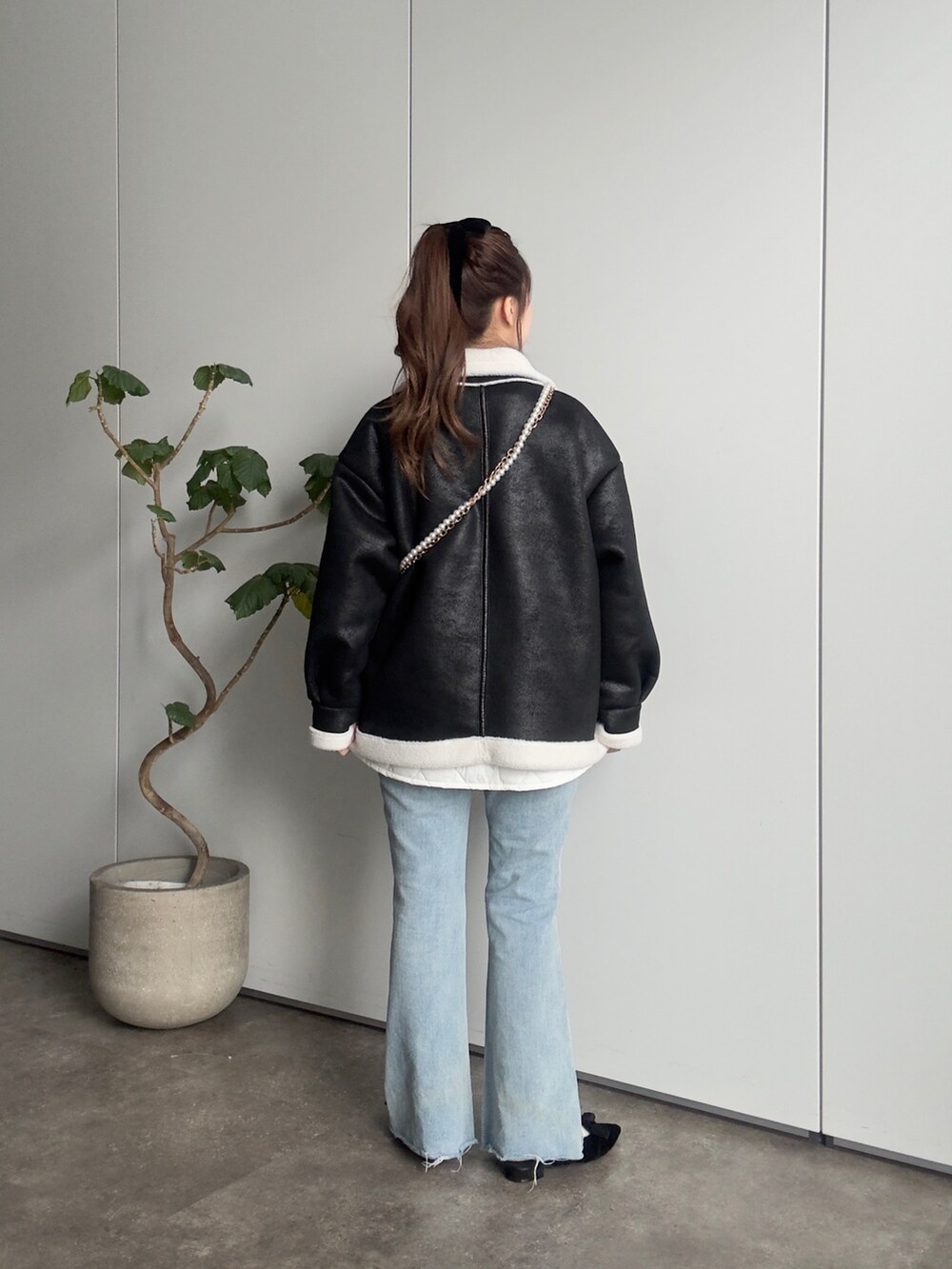 ブラック系のムートンコート、ベージュ系のTシャツ/カットソー、ブラック系のショルダーバッグを着用したレディースの冬コーディネートの3枚目の写真