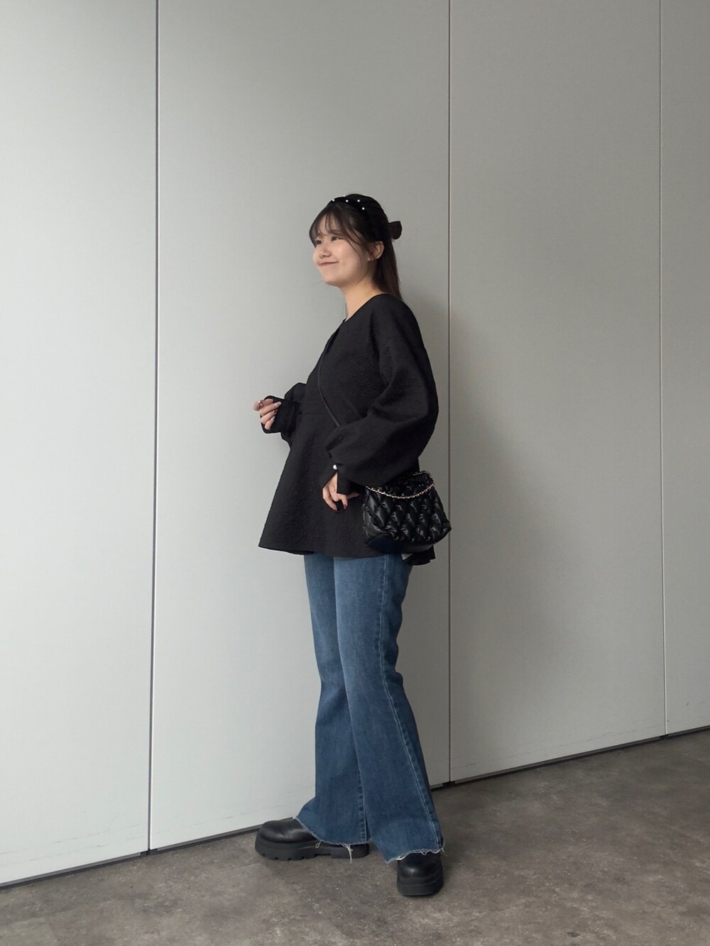 ブラック系のシャツ/ブラウス、ブラック系のショルダーバッグ、ブルー系のデニムパンツを着用したレディースの冬コーディネートの2枚目の写真