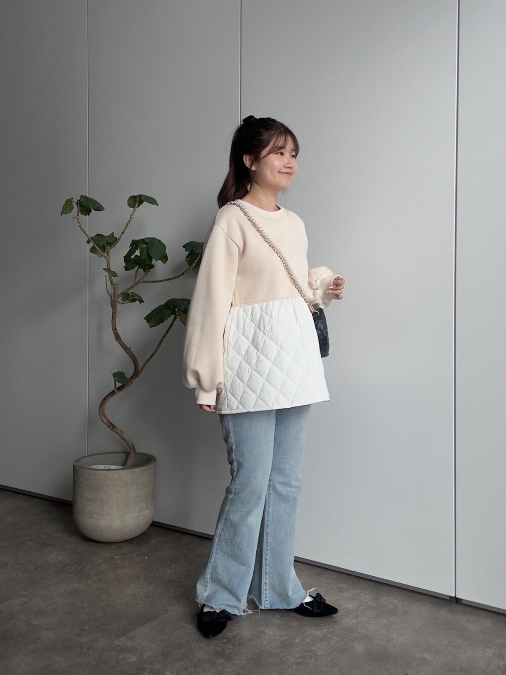 ベージュ系のTシャツ/カットソー、ブラック系のショルダーバッグ、ブルー系のデニムパンツを着用したレディースの冬コーディネートの2枚目の写真