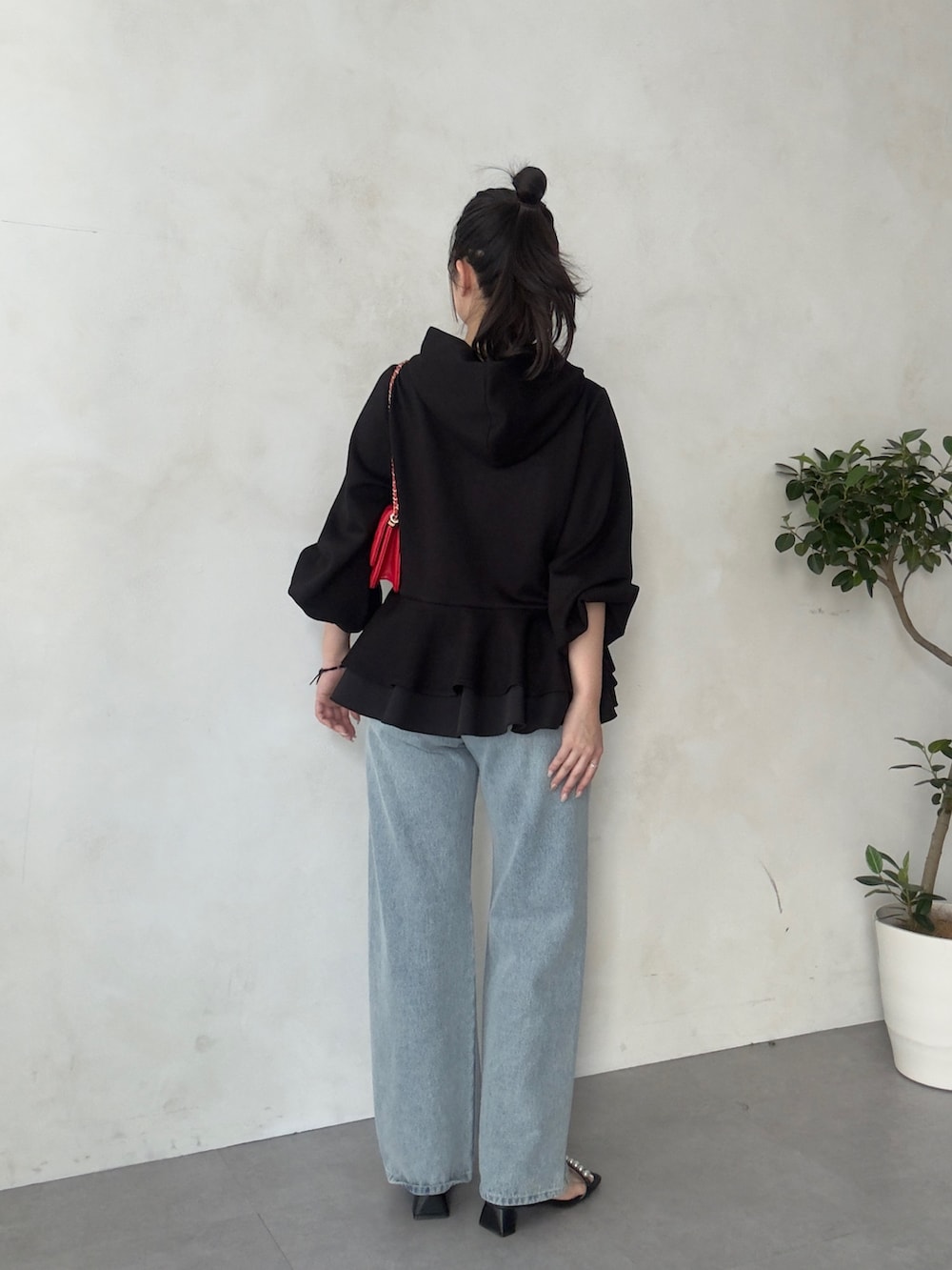 レッド系のトートバッグ、ブラック系のサンダル、ブラック系のパーカーを着用したレディースの春コーディネートの3枚目の写真