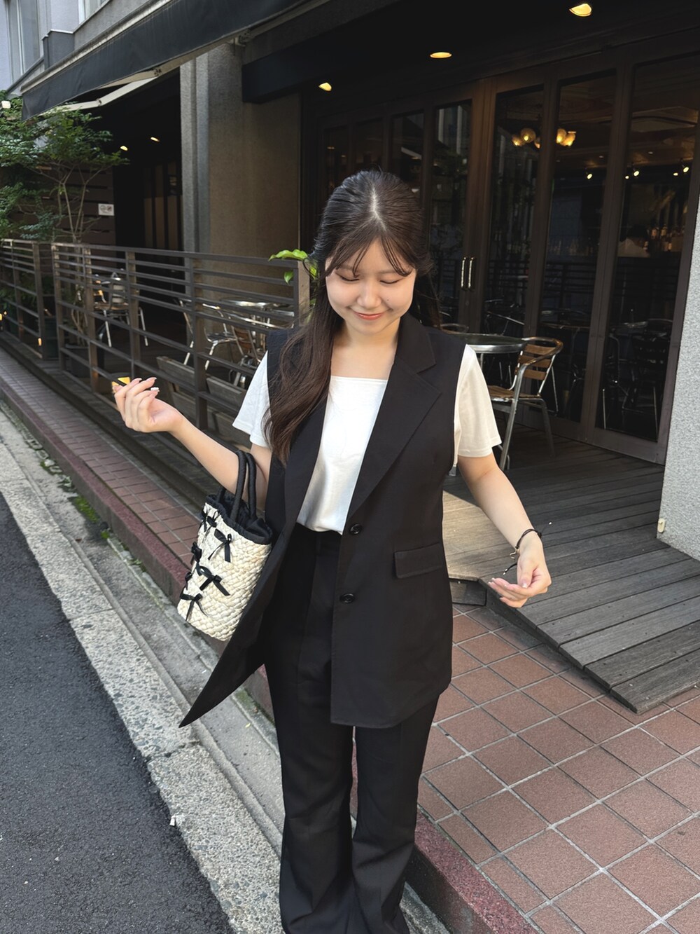 ホワイト系のTシャツ/カットソー、ブラック系のベスト、ブラック系のかごバッグを着用したレディースの夏コーディネートの3枚目の写真