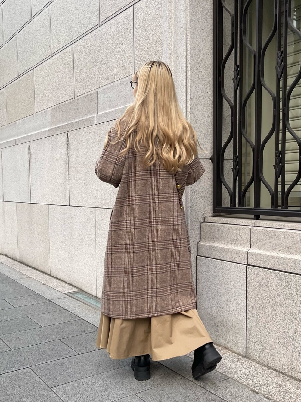 ホワイト系のニット/セーター、ブラウン系のチェスターコート、ベージュ系のスカートを着用したレディースの秋コーディネートの5枚目の写真