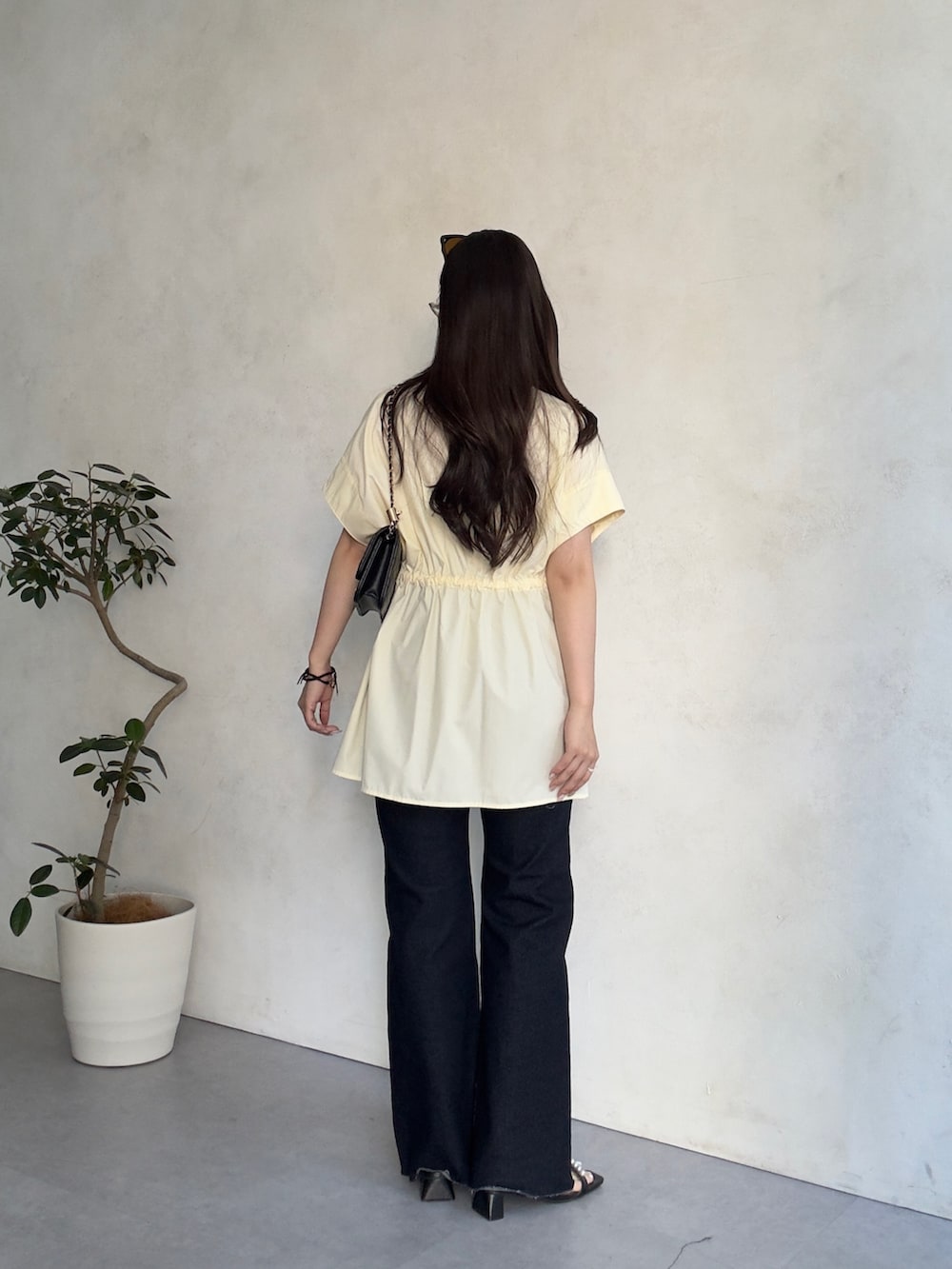 ブルー系のデニムパンツ、ブラック系のサンダル、ブラック系のトートバッグを着用したレディースの夏コーディネートの3枚目の写真