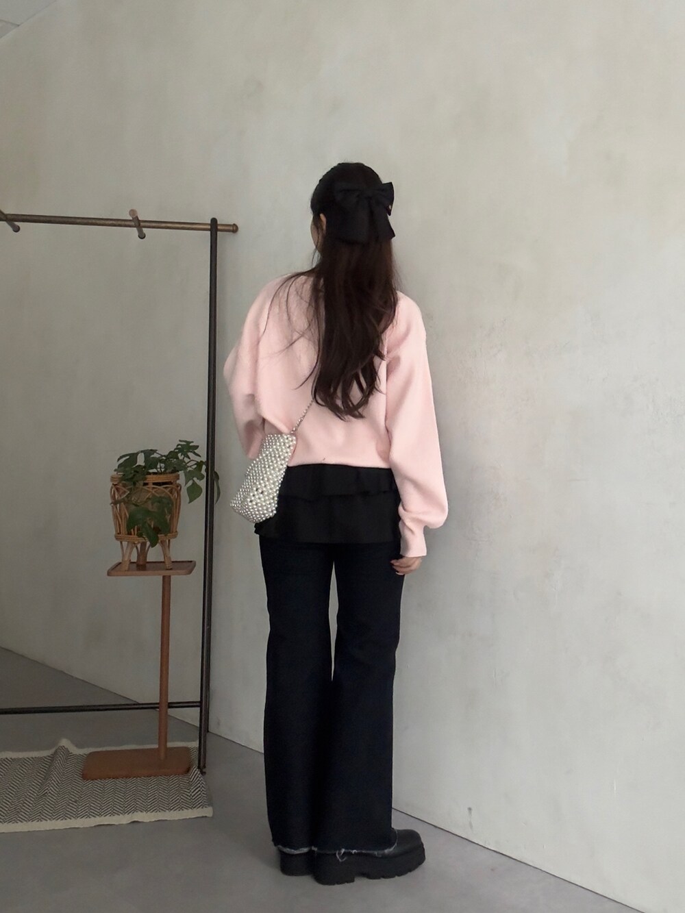 ピンク系のニット/セーター、ブラック系のスカート、ブルー系のデニムパンツを着用したレディースの秋コーディネートの3枚目の写真