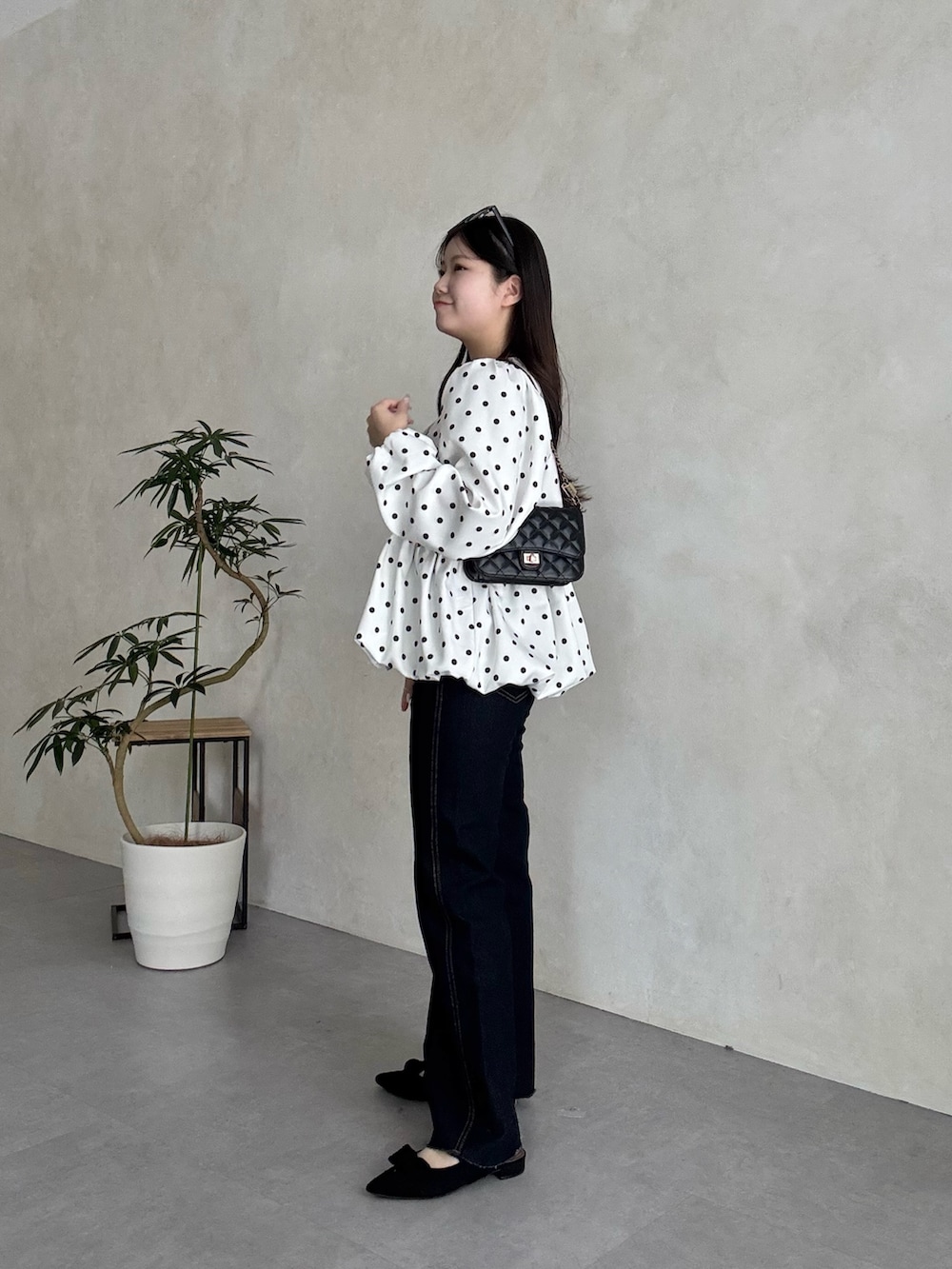 ブラック系のトートバッグ、ブルー系のデニムパンツ、ブラック系のパンプスを着用したレディースの春コーディネートの2枚目の写真