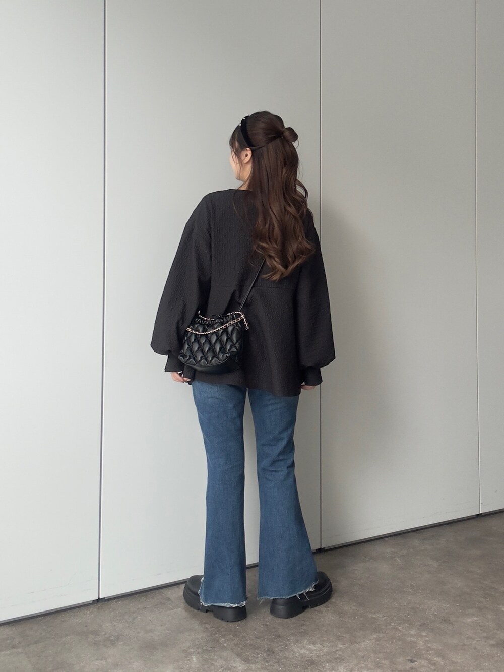 ブラック系のシャツ/ブラウス、ブラック系のショルダーバッグ、ブルー系のデニムパンツを着用したレディースの冬コーディネートの3枚目の写真