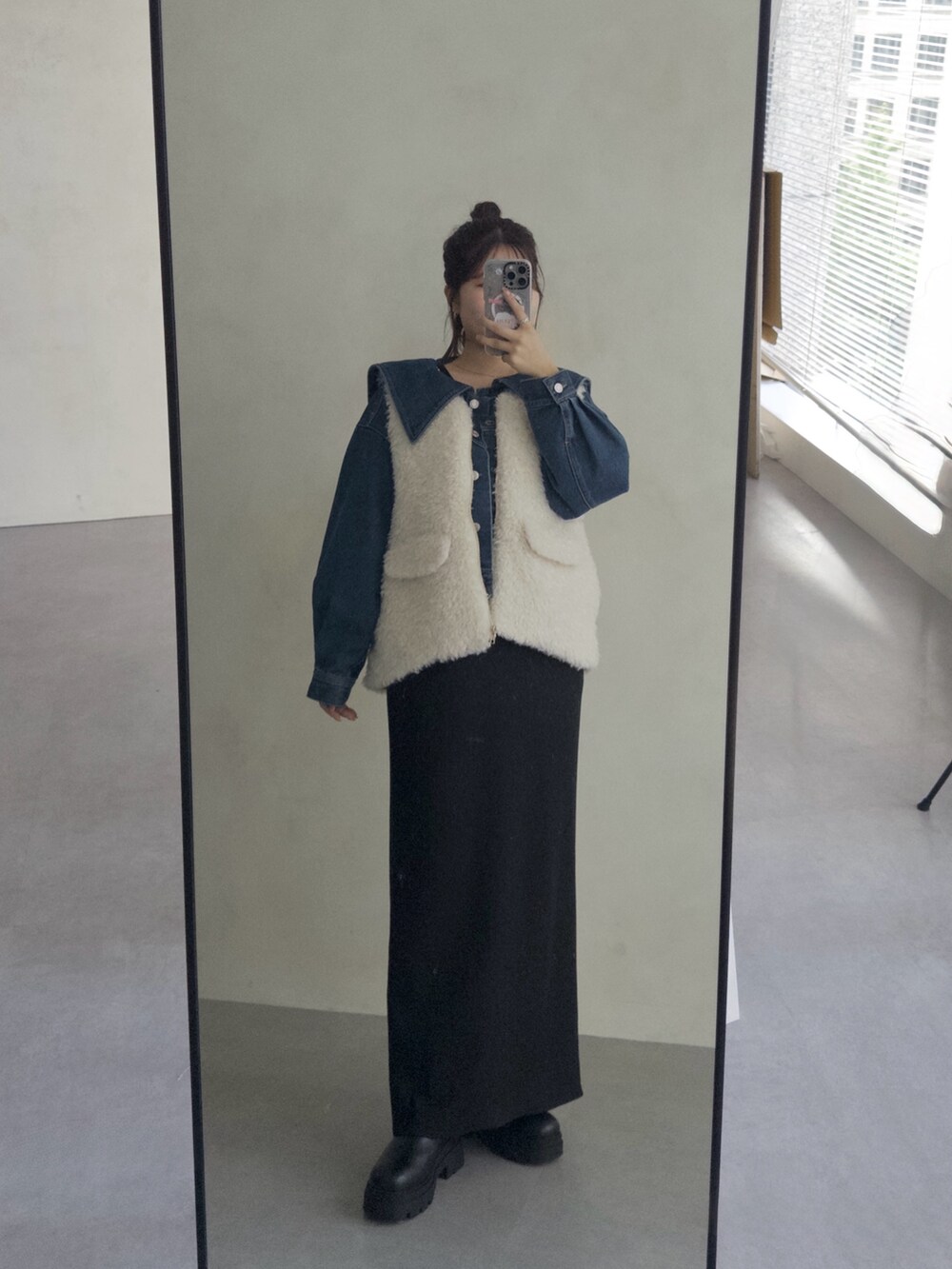 ブルー系のデニムジャケット、ブラック系のスカート、ブラック系のブーツを着用したレディースの夏コーディネートの3枚目の写真