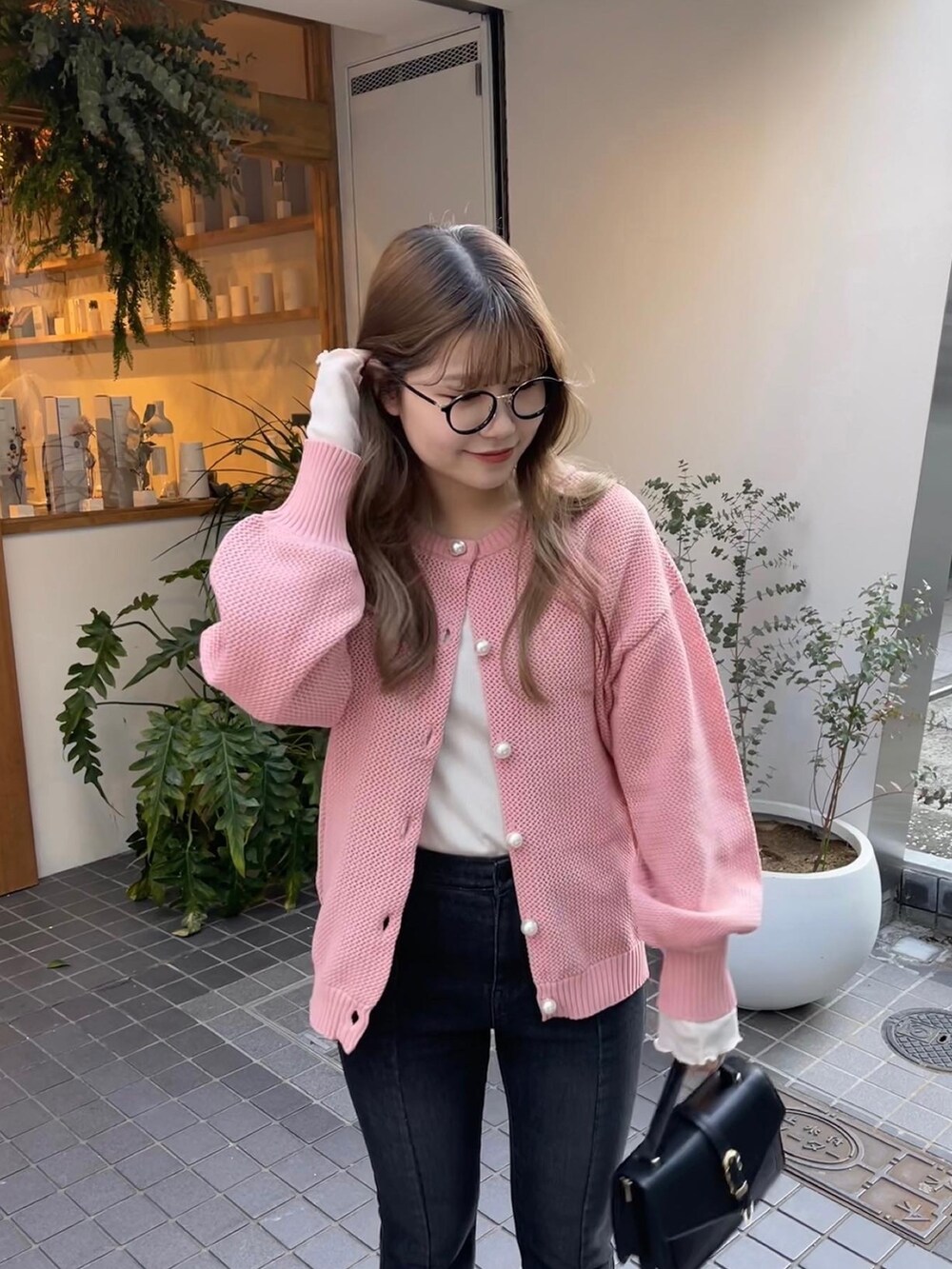 ピンク系のカーディガン/ボレロ、ホワイト系のTシャツ/カットソー、ブラック系のブーツを着用したレディースの冬コーディネートの2枚目の写真