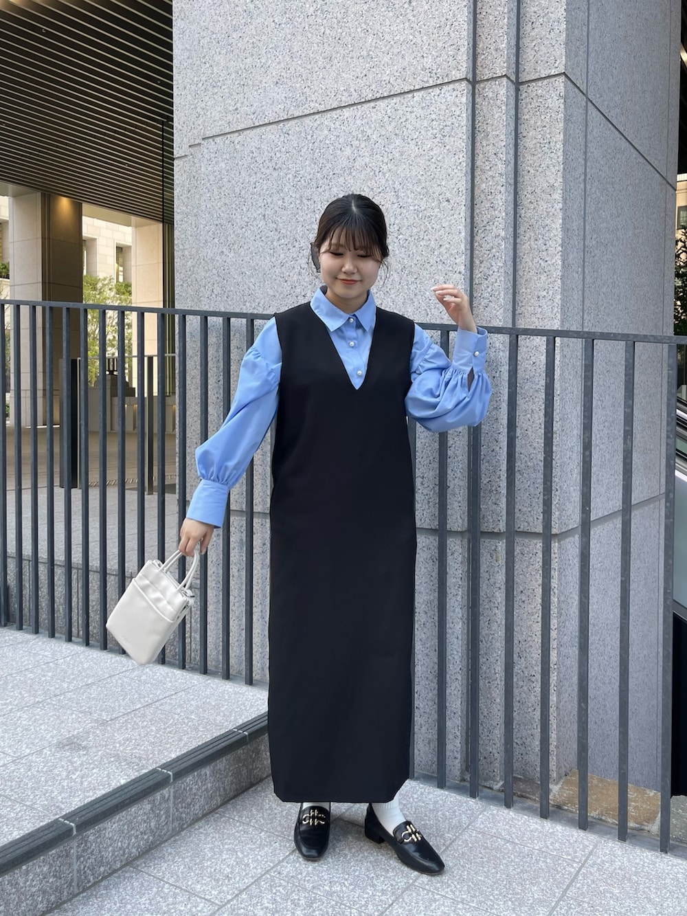 ブルー系のシャツ/ブラウス、ブラック系のローファー、ブラック系のジャンパースカートを着用したレディースの春コーディネートの3枚目の写真