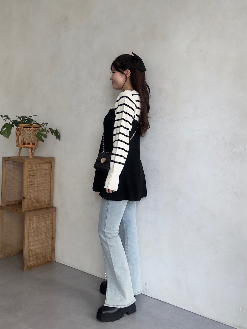 ホワイト系のニット/セーター、ブルー系のデニムパンツ、ブラック系のブーツを着用したレディースの秋コーディネートの2枚目の写真