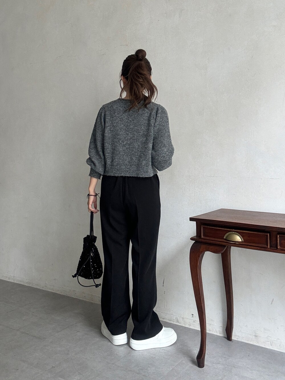 グレー系のニット/セーター、ブラック系のその他パンツ、ホワイト系のスニーカーを着用したレディースの秋コーディネートの3枚目の写真