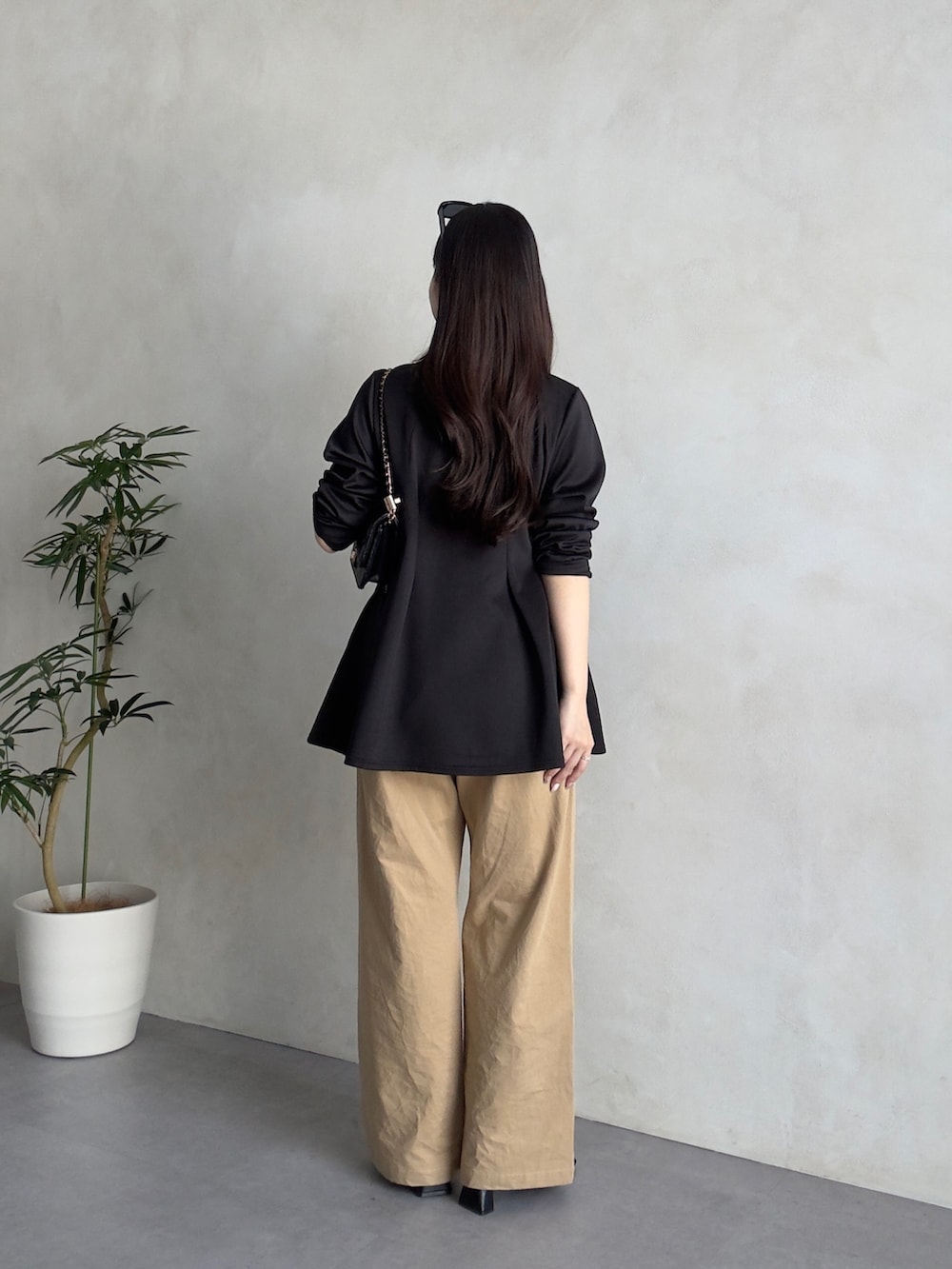 ブラック系のトートバッグ、ベージュ系のチノパンツ、ブラック系のサンダルを着用したレディースの春コーディネートの3枚目の写真