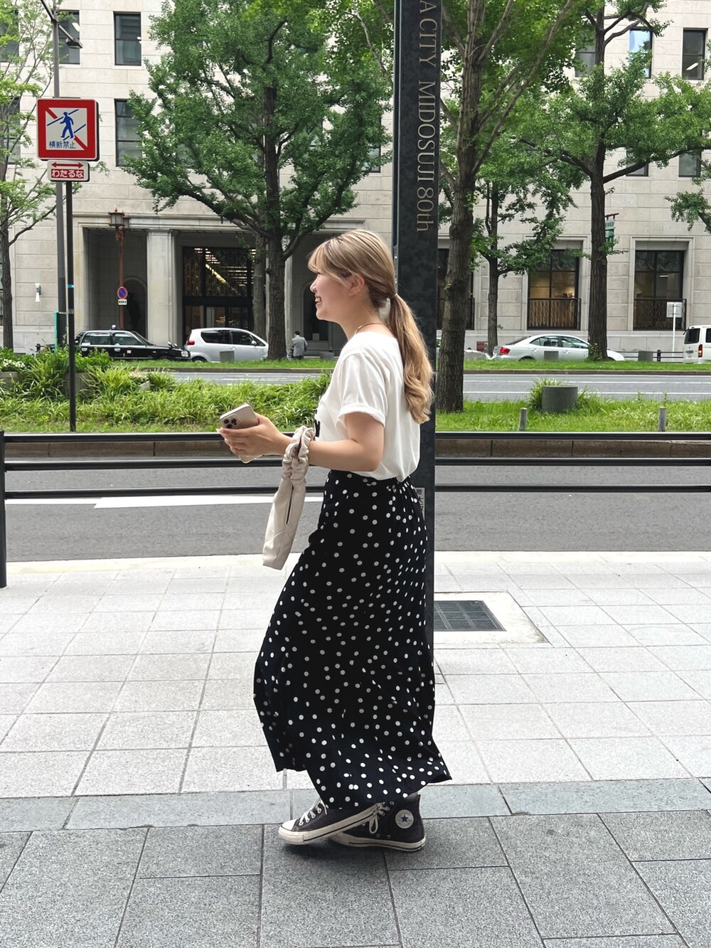 ホワイト系のTシャツ/カットソー、ホワイト系のハンドバッグ、ブラック系のスカートを着用したレディースの夏コーディネートの2枚目の写真