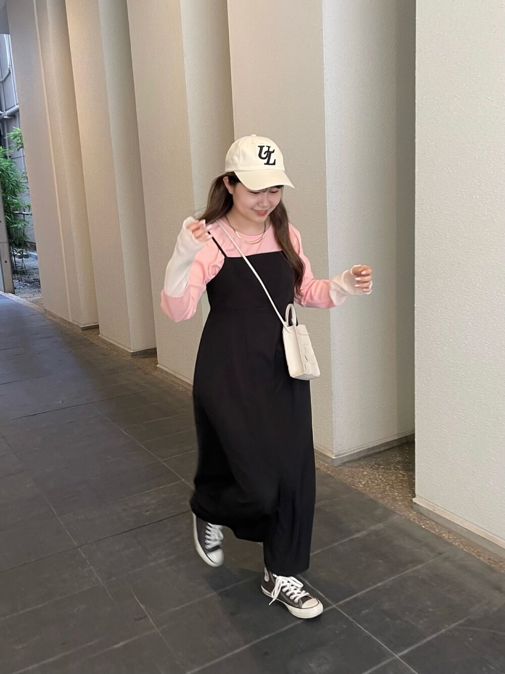 ピンク系のTシャツ/カットソー、ブラック系のワンピース、ホワイト系のキャップを着用したレディースの春コーディネートの3枚目の写真