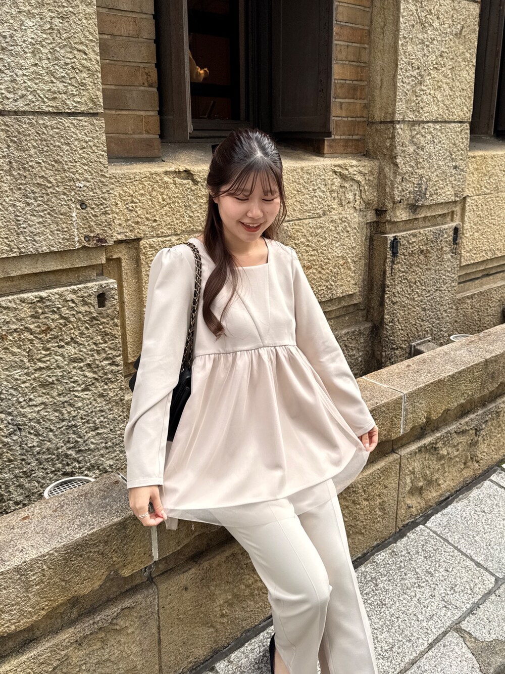 ベージュ系のシャツ/ブラウス、ブラック系のショルダーバッグ、ベージュ系のスラックスを着用したレディースの冬コーディネートの2枚目の写真