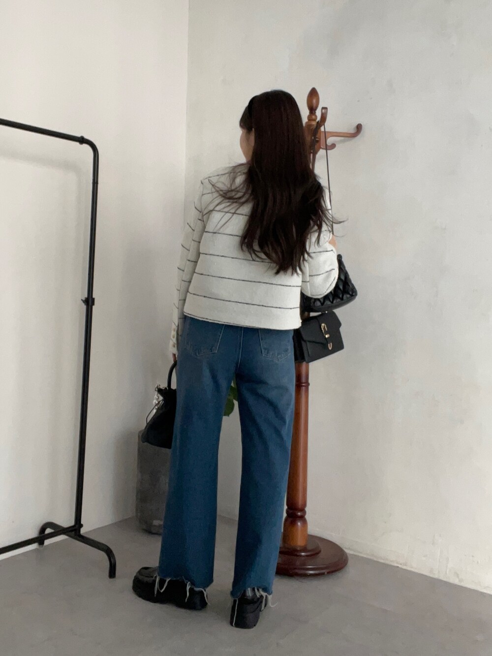 グレー系のニット/セーター、ブルー系のデニムパンツ、ブラック系のショルダーバッグを着用したレディースの冬コーディネートの2枚目の写真