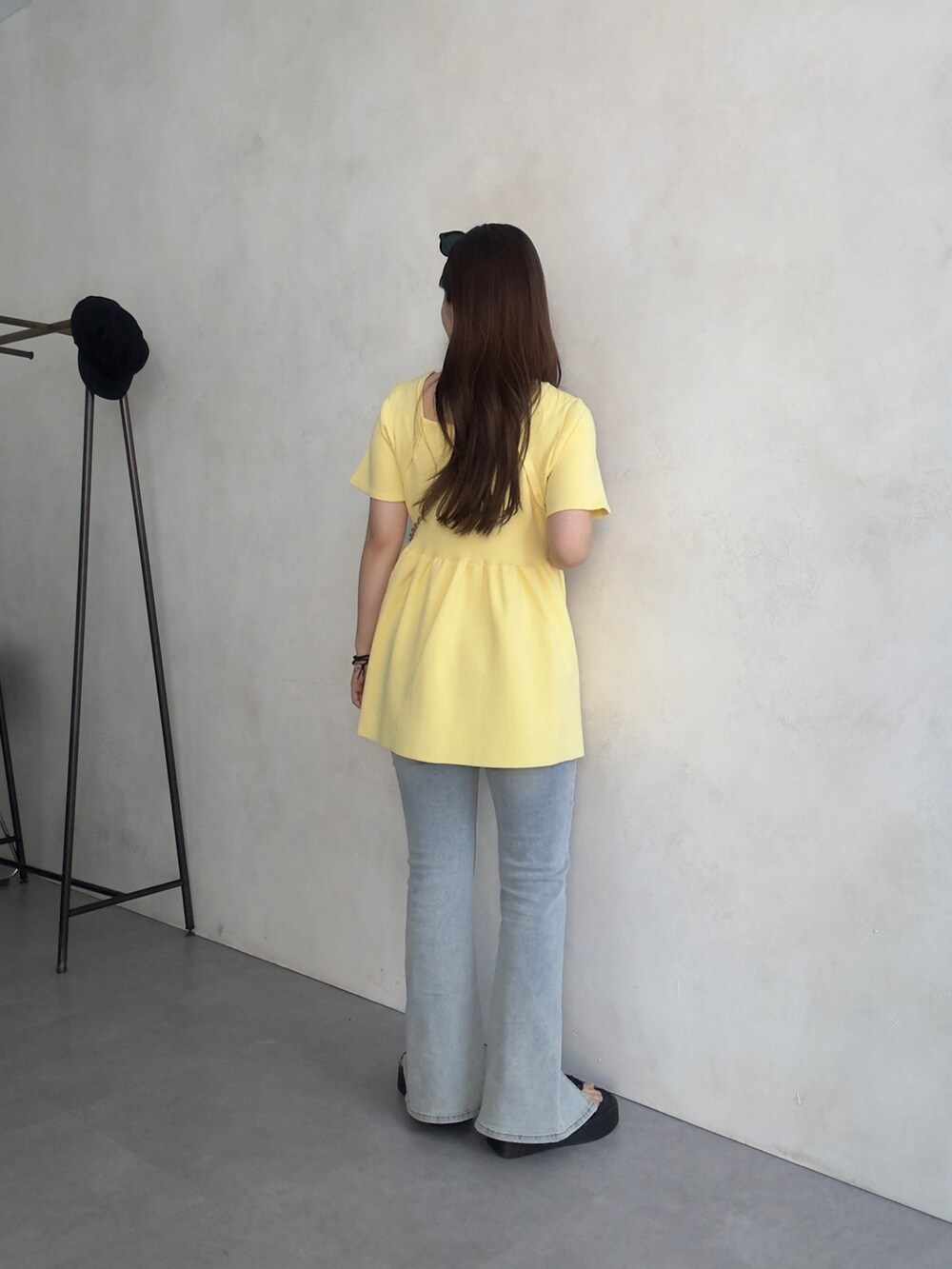 イエロー系のニット/セーター、ブルー系のデニムパンツ、ブラック系のサンダルを着用したレディースの夏コーディネートの3枚目の写真