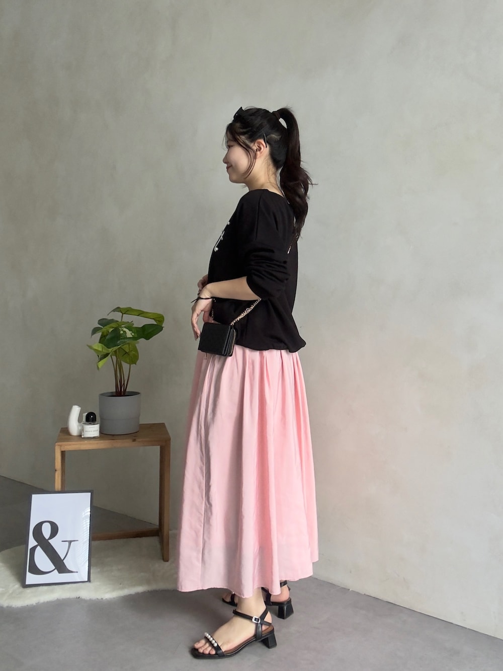 ブラック系のスウェット、ピンク系のスカート、ブラック系の財布を着用したレディースの冬コーディネートの3枚目の写真