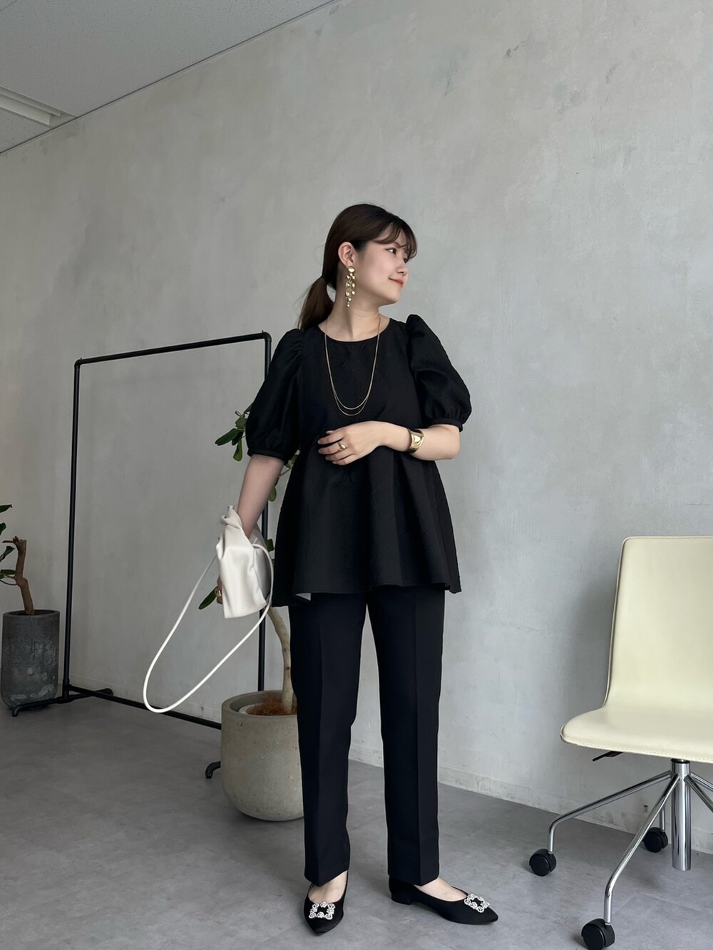 ブラック系のパンプス、ブラック系のパンツドレス、ゴールド系のネックレスを着用したレディースの春コーディネートの2枚目の写真