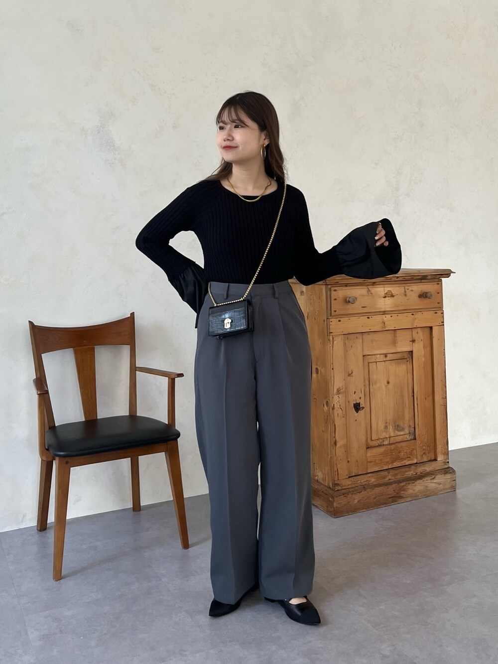 ブラック系のパンプス、ブラック系のニット/セーター、グレー系のスラックスを着用したレディースの秋コーディネートの2枚目の写真