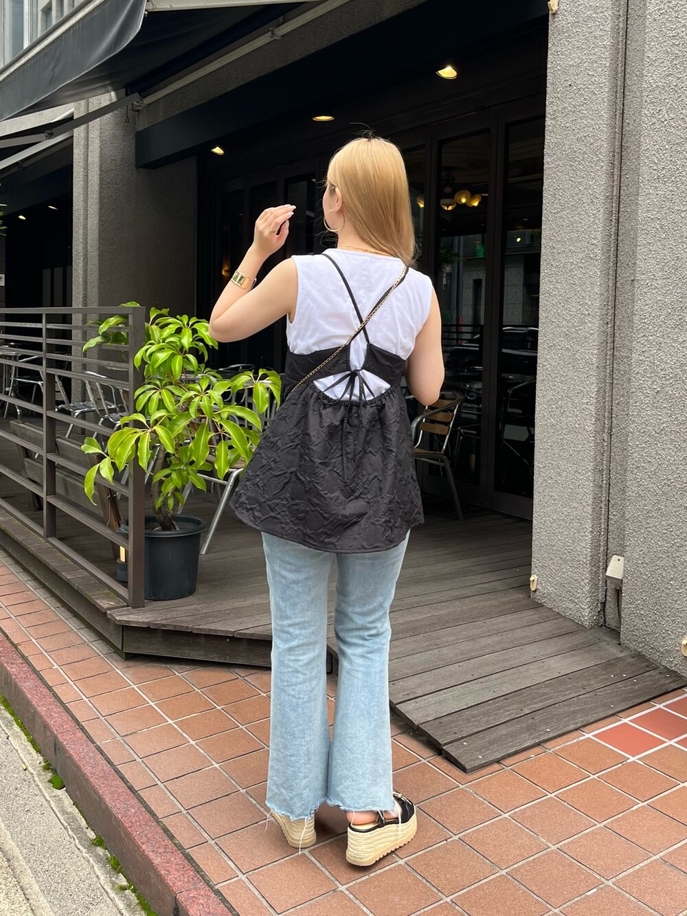 ブラック系のキャミソール、ベージュ系のショルダーバッグ、ブルー系のデニムパンツを着用したレディースの夏コーディネートの3枚目の写真