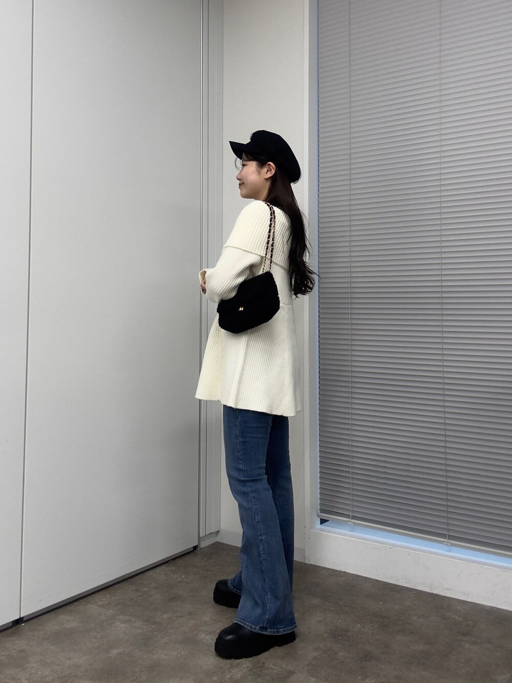 ブラック系のショルダーバッグ、ホワイト系のニット/セーター、ブルー系のデニムパンツを着用したレディースの秋コーディネートの2枚目の写真