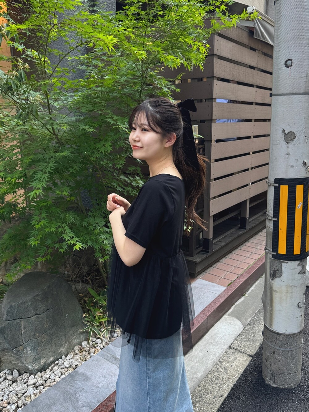 ブラック系のショルダーバッグ、ブラック系のTシャツ/カットソー、ブルー系のデニムスカートを着用したレディースの春コーディネートの4枚目の写真