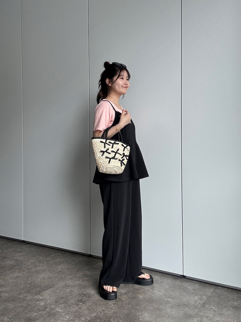 ブラック系のサロペット/オーバーオール、ブラック系のサンダル、ブラック系のかごバッグを着用したレディースの春コーディネートの2枚目の写真