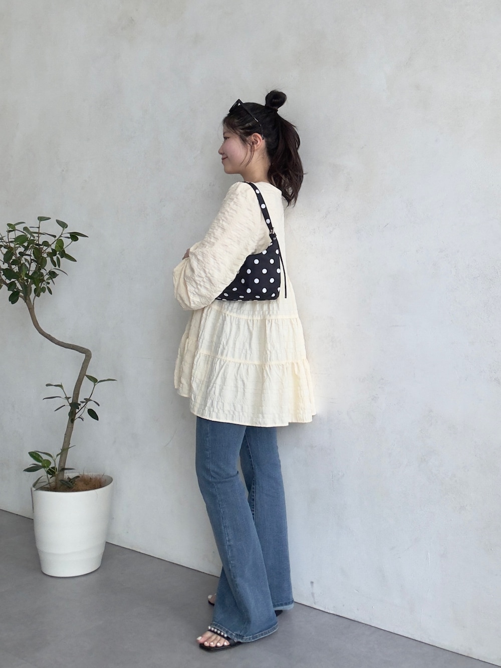 ブルー系のデニムパンツ、ブラック系のサンダル、ベージュ系のシャツ/ブラウスを着用したレディースの春コーディネートの2枚目の写真